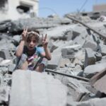 Meisje dat het vredesteken maakt, tussen het puin in Gaza