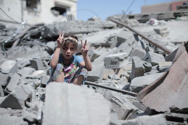 Meisje dat het vredesteken maakt, tussen het puin in Gaza